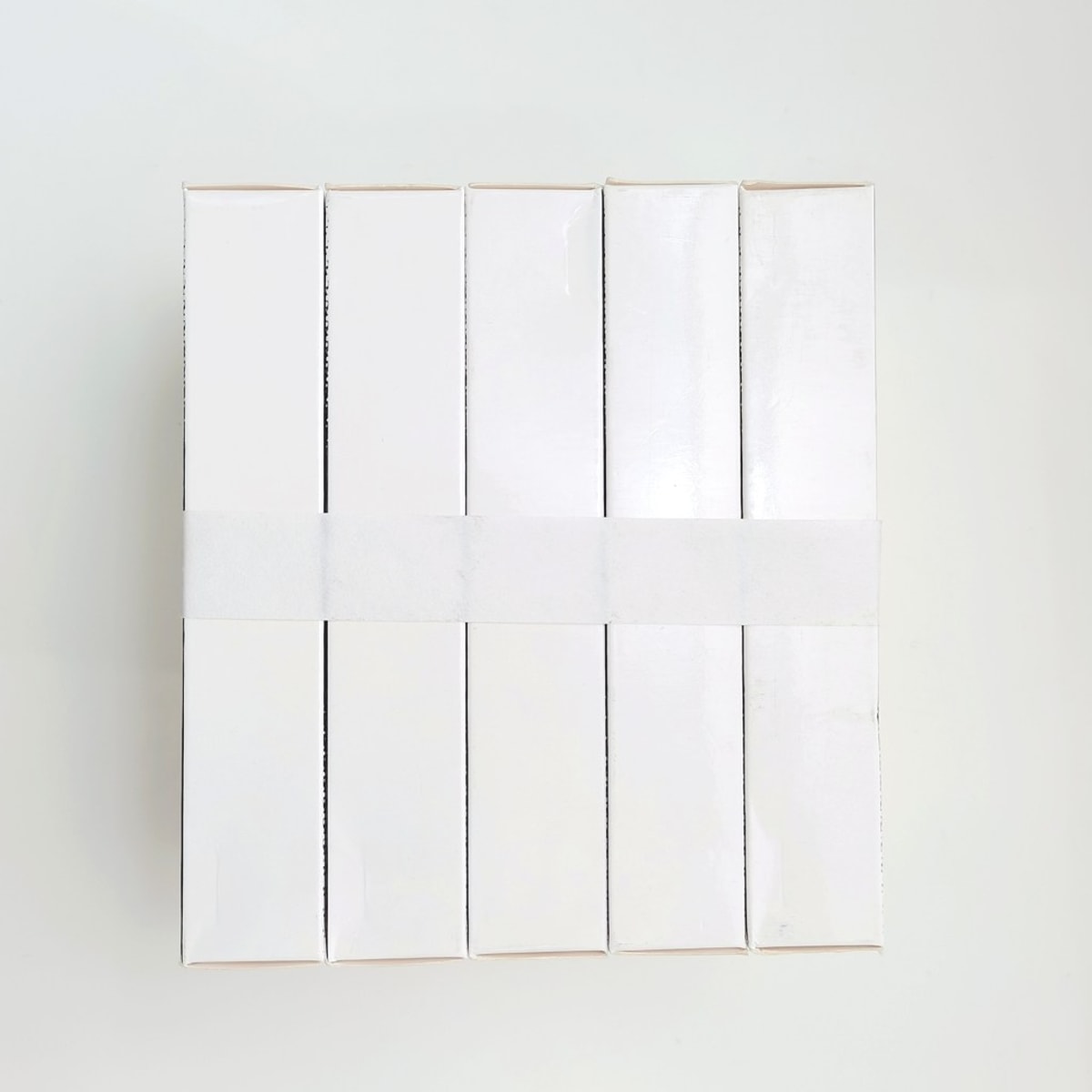Cinq boîtes blanches regroupées par une bande, banderoleuse SUNPACK WK02-30