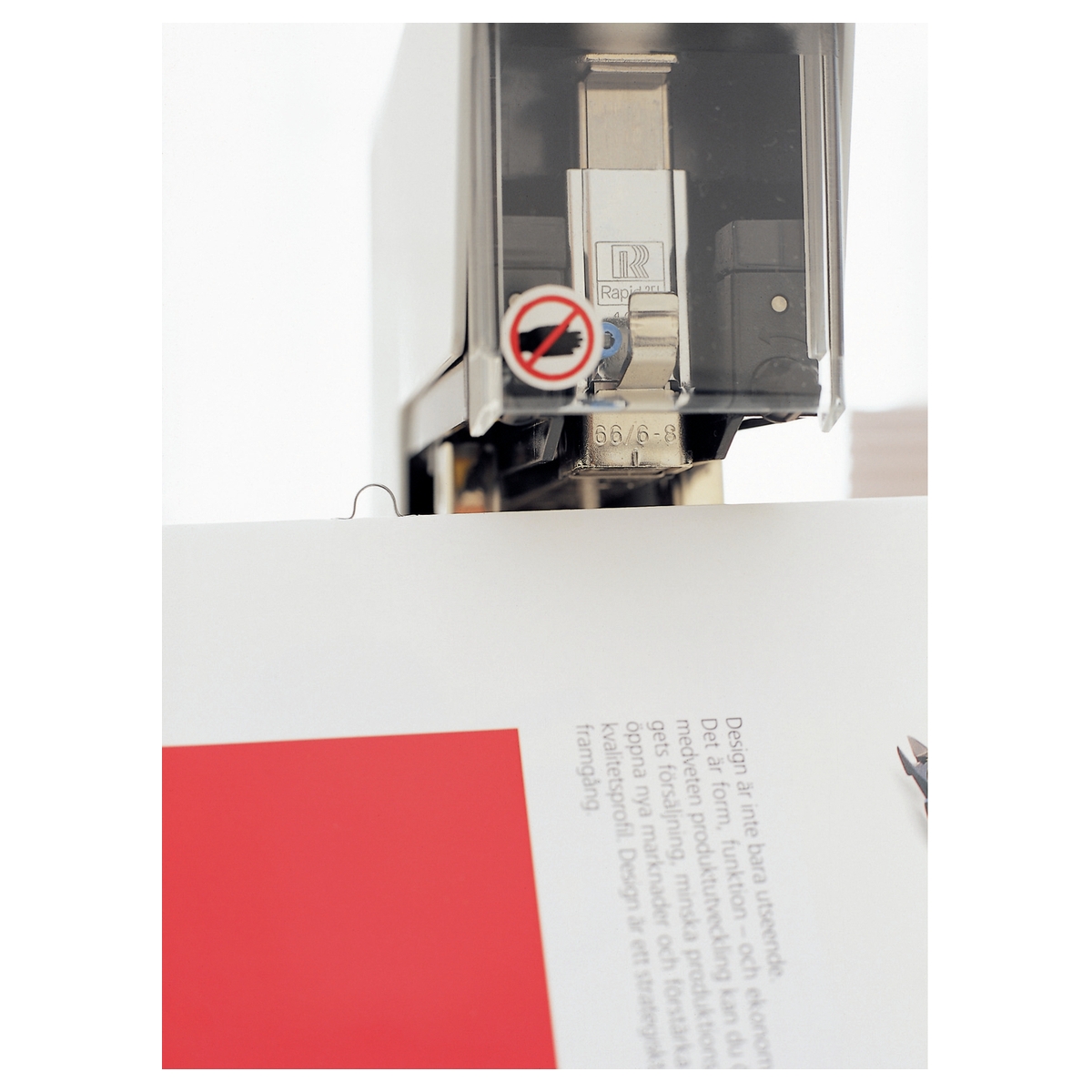 Tête d'agrafage de l'agrafeuse électrique de livrets RAPID Classic 106E au-dessus d'une brochure.