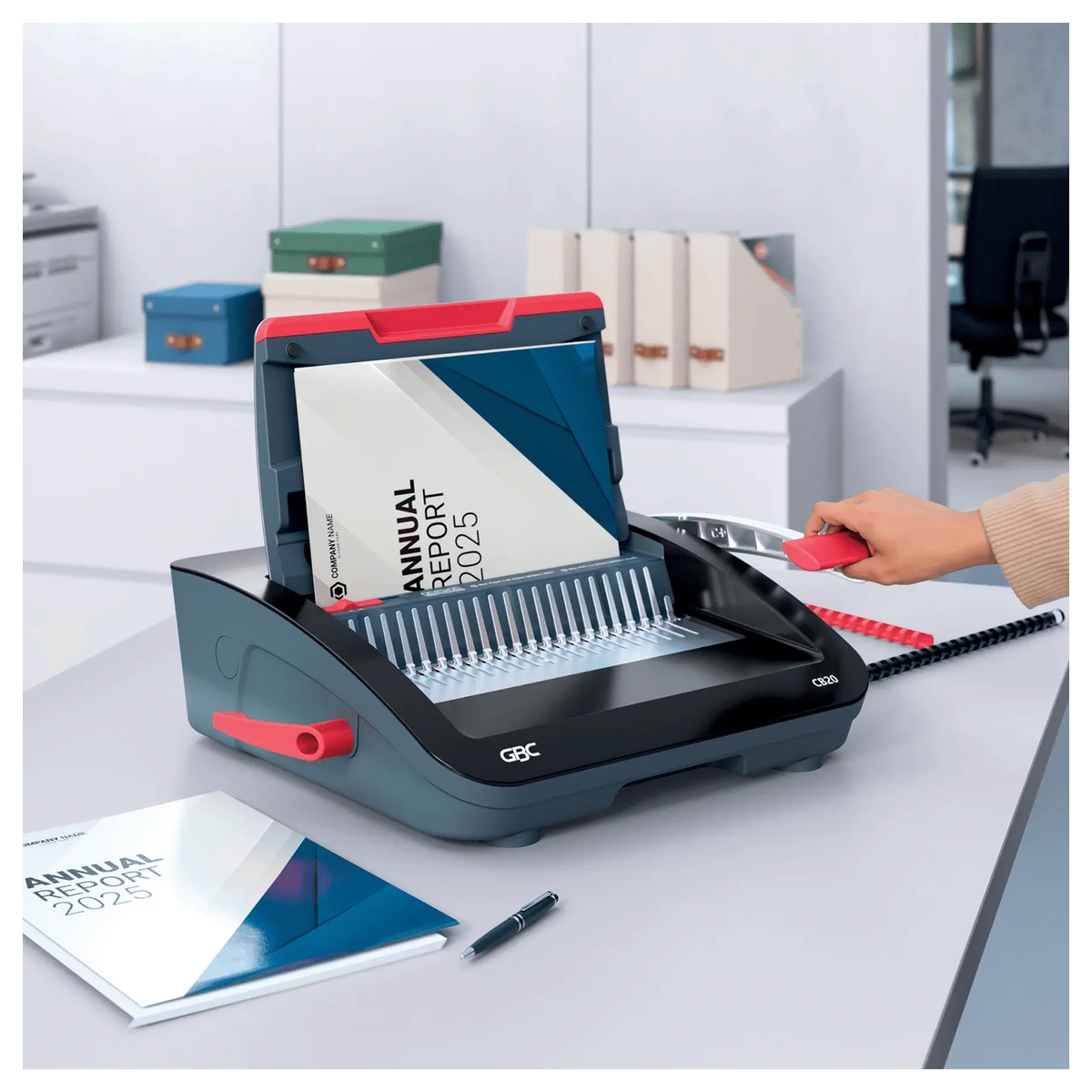 Perforelieuse GBC CombBind CB20 sur un bureau, feuilles engagées dans le peigne plastique.