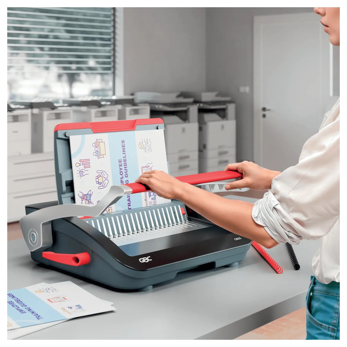 Perforelieuse GBC CombBind CB25 en usage sur un bureau, peigne ouvert pour la reliure.